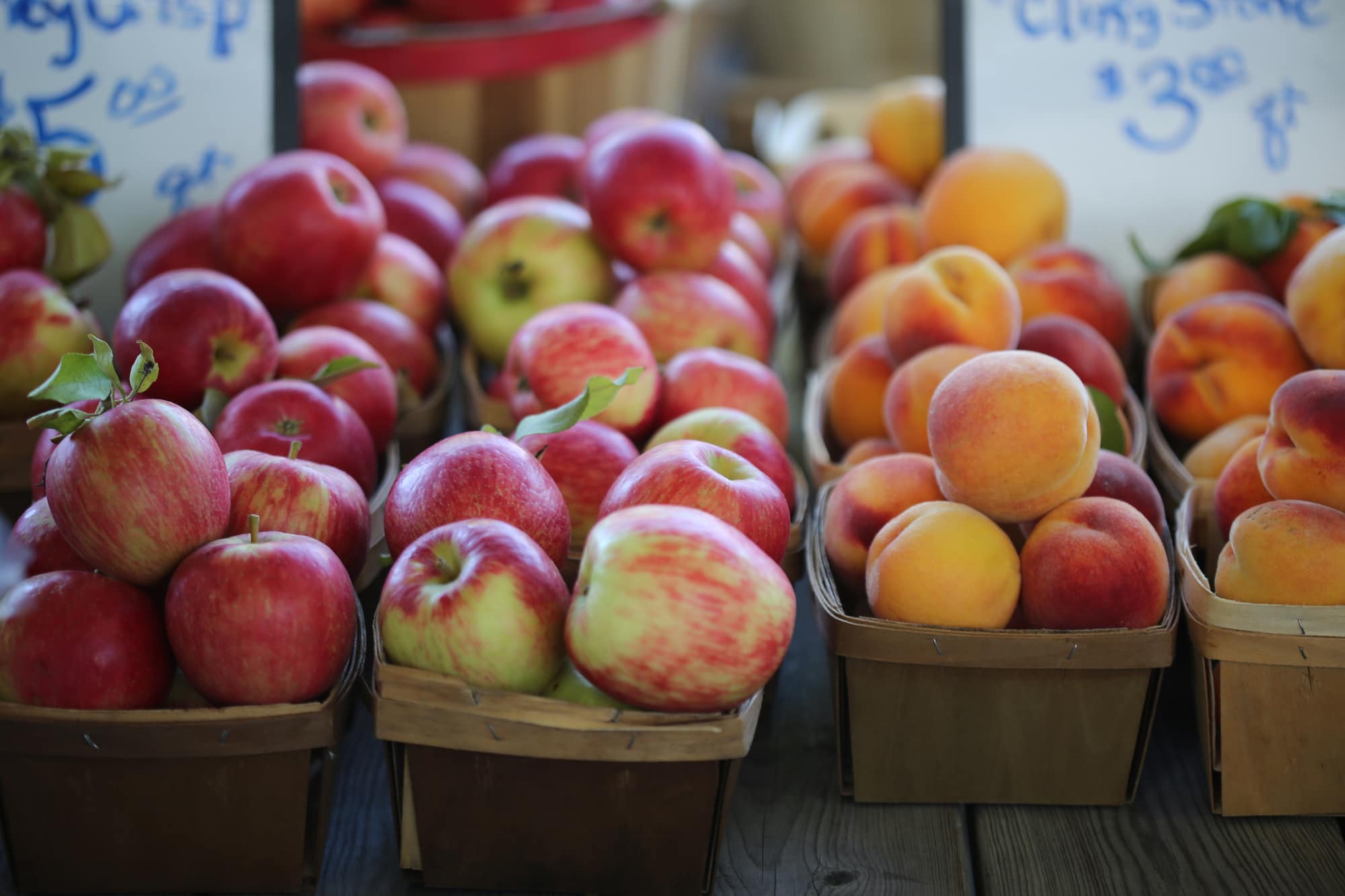 Quart baskets of apples and peaches at a farm stand